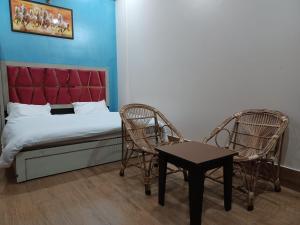 Rāni PokhriParadise Home stay的一间卧室配有一张床、两把椅子和一张桌子