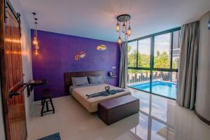 盼武里เเองเจล่า รีสอร์ท的一间卧室设有紫色墙壁、一张床和一个游泳池