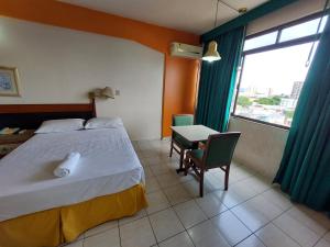 马瑙斯泰姬陵酒店 的一间卧室配有一张床、一张桌子和一个窗户。