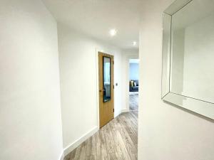 沃尔索尔Rooms Near Me - Walsall City Centre Apartment的一条带白色墙壁和木门的走廊