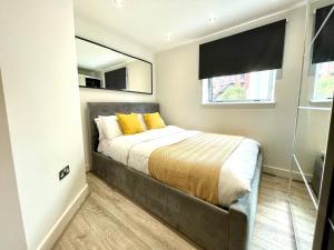 沃尔索尔Rooms Near Me - Walsall City Centre Apartment的一间卧室配有一张带黄色枕头的床和一扇窗户