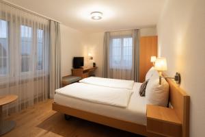 施维茨Wysses Rössli Swiss Quality Hotel的一间卧室配有一张床、一张书桌和一台电视