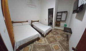 CarepaHotel San Adolfo Carepa的小型客房的两张床,铺有地板