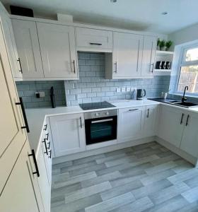 Water OrtonSt Blaise的厨房配有白色橱柜和瓷砖地板。