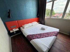 波德申双赢精品PD酒店的一间卧室配有一张带橙色床头板和窗户的床。