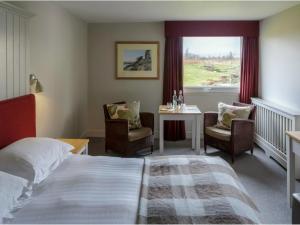 蒂贝Westmorland Hotel Tebay的酒店客房带一张床、一张桌子和椅子