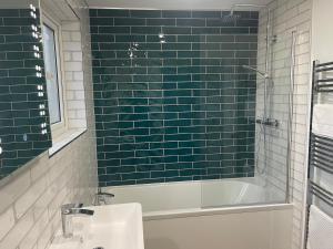 彭布罗克郡Furzy House的浴室铺有绿色地铁瓷砖,配有浴缸和水槽。