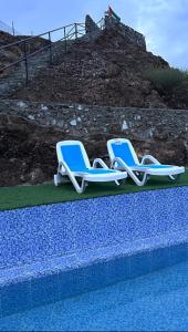 Alhara Lodge استراحة الحارة的游泳池旁的两把蓝色和白色躺椅