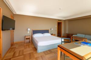 那不勒斯皇家大陆酒店的一间卧室配有一张床、一张桌子和一台电视。