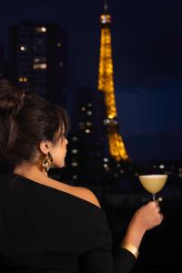 巴黎Quinzerie hôtel的一位在艾菲尔铁塔前拿着酒杯的女人