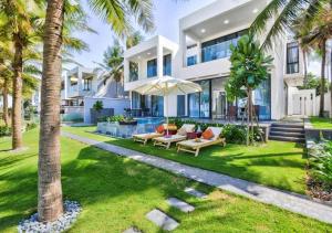 岘港Vacation Home Ocean Villas的一座大型白色房子,前面有棕榈树