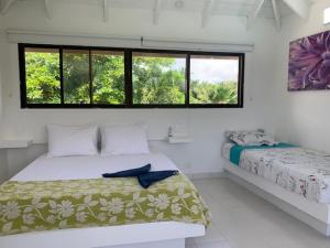 圣安德烈斯Casa de las Flores tropical的白色的客房设有两张床和窗户。