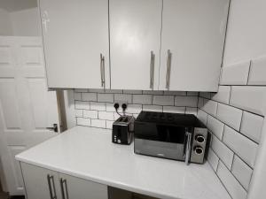 利物浦Goodison Accommodation的厨房柜台配有微波炉和白色橱柜。