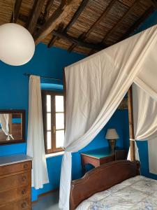 夸尔图-圣埃莱娜Antica Dimora的一间拥有蓝色墙壁的卧室和一张带天蓬的床