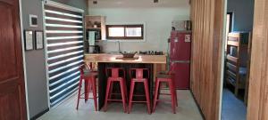 普孔Pucón Rec-Lodge Camino al Volcan的厨房里设有红色凳子,厨房里设有红色凳子
