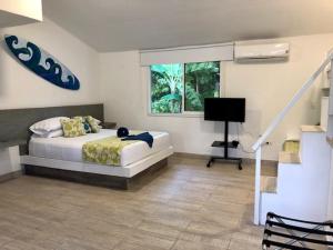 圣安德烈斯Casa de las Flores tropical的一间卧室配有一张床、一张书桌和一个窗户。