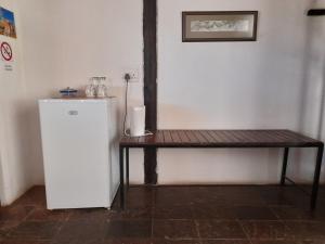 奥奇瓦龙戈Lion's Den Guesthouse Otjiwarongo的一张木桌旁的白色小冰箱