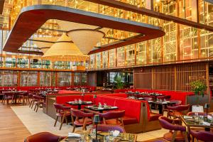 迪拜迪拜皇冠酒店的一间设有红色椅子和桌子及灯的餐厅