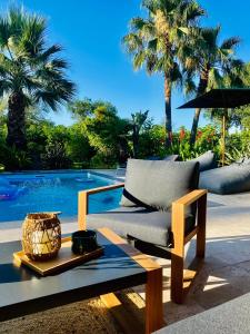 索利耶蓬Le Cocoon Lodge du Gapeau & Massage的一张沙发,坐在游泳池旁的桌子上