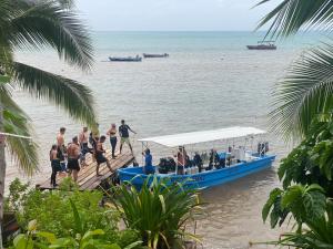 小玉米岛Las Palmeras OceanView Hotel and Dive Center的一群人乘坐蓝色的船在海滩上