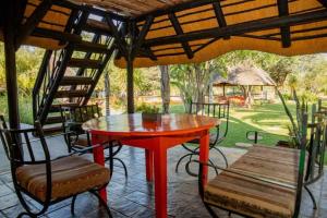 奥奇瓦龙戈Lion's Den Guesthouse Otjiwarongo的露台上的红色桌椅