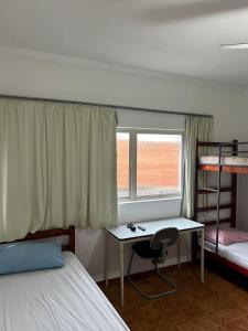 平达莫尼扬加巴Hotel Pousada Liberdade的一间卧室配有书桌、一张床和双层床。