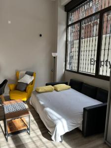 马德里Estudio céntrico zona palacio的一间卧室配有一张大床和一张黄色椅子