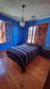 马德普拉塔El Fortin的一间卧室配有一张蓝色墙壁和木地板。
