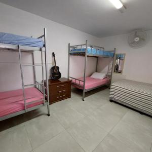 帕苏斯Hostel Muarama的一间设有三张双层床和吉他的房间