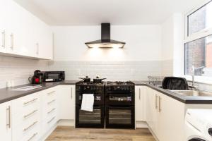 奥尔德姆Suite 4 - Trendy Spot in Oldham City Centre的厨房配有白色橱柜和黑色家电