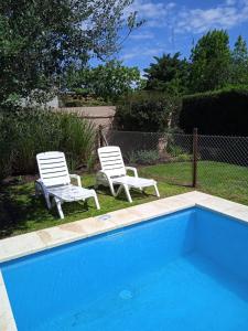 洛博斯Casa Los Trinos的两把白色椅子坐在游泳池旁
