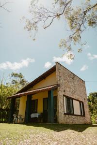 穆隆古Villa Nova Holanda的前面有椅子的小黄色房子