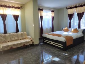 西隆Vati guesthouse的一间卧室配有一张床、一张沙发和窗户。