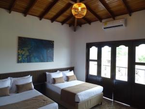 Playa VerdeHotel Palmas De Alcalá的一间卧室配有两张床和吊灯。