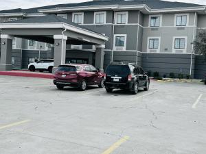 斯托克顿堡Fort Stockton Inn and Suites的两辆汽车停在大楼前的停车场