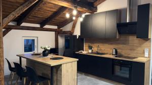 卡托维兹Parkcity Katowice Bogucice的一间厨房,配有黑色橱柜和一个带椅子的岛屿