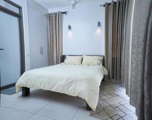 VipingoMonarch Villas - Kilifi的一间卧室配有一张带白色床单的床和一扇窗户。