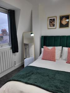 伦敦20 mins to central London, Stylish sky views 2 bed的一间卧室配有一张带绿色床头板和镜子的床