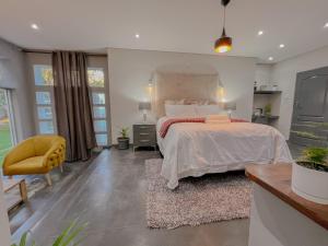 约翰内斯堡Amoris Guesthouse - Sandton的一间卧室配有一张大床和一张黄色椅子