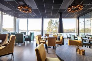 RømskogRømskog Spa & Resort - Unike Hoteller的餐厅设有桌椅和大窗户。
