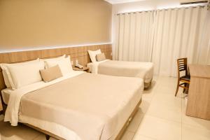 圣安娜-利弗拉门图Confort Fronteira Hotel的酒店客房配有两张床和一张书桌