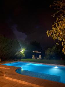 圣拉斐尔Posada “LA MARGARITA”的夜间游泳池,配有桌子和遮阳伞