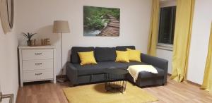 维也纳新城Top Appartement für Business-Wohnen-Urlaub的客厅配有灰色的沙发和黄色的枕头。