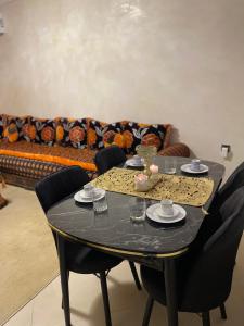 马拉喀什Kech Days appartement près de l'aéroport的客厅配有一张带椅子的黑色桌子和一张沙发。