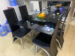拉各斯The Residence Golden Tulip 2 Bedroom Apartment, Amuwo Lagos, Nigeria的餐桌,椅子和一碗水果