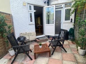 The HydeLovely one bedroom garden flat in Hendon的庭院设有两把椅子、一张桌子和烤架。