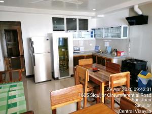 SolangonTropicasa Siquijor Seafront Guest House的厨房配有桌子和冰箱
