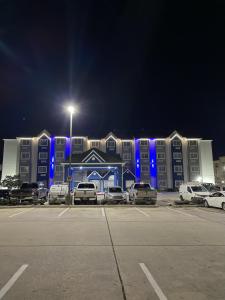 巴吞鲁日巴敦罗吉机场麦克罗特套房酒店的蓝色灯的建筑前的停车场
