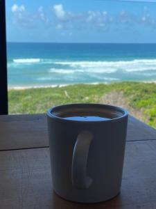 格伦塔纳Marien Beach House的坐在窗前的桌子上喝杯咖啡