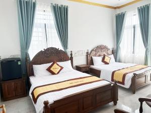 Chợ Phước HảiHotel Quốc Hương的一间卧室设有两张床、一台电视和窗户。